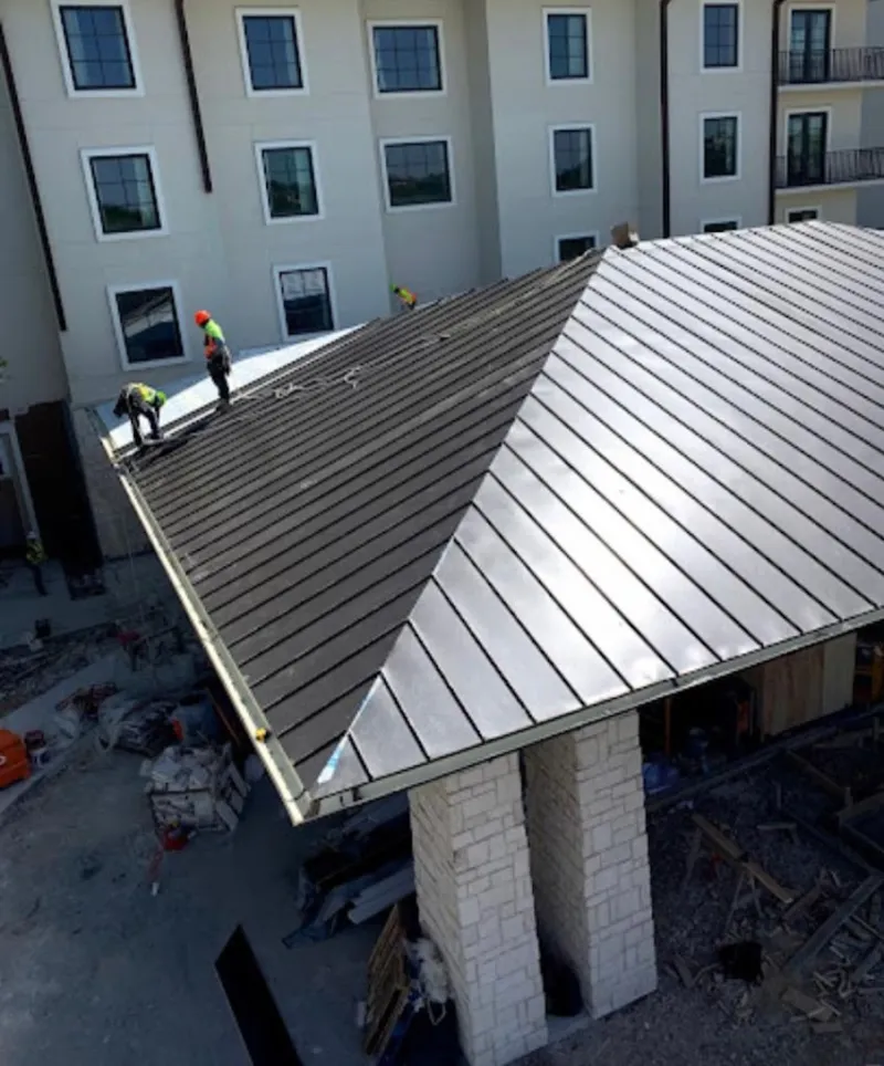 Crew installing standing seam metal roof panels on a commercial project in Basehor